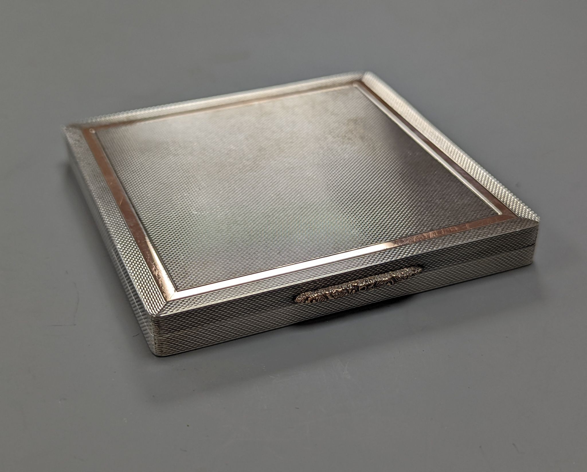 A 1960's Garrard & Co yellow metal mounted engine turned silver cigarette case, Birmingham, 1965, 88mm.